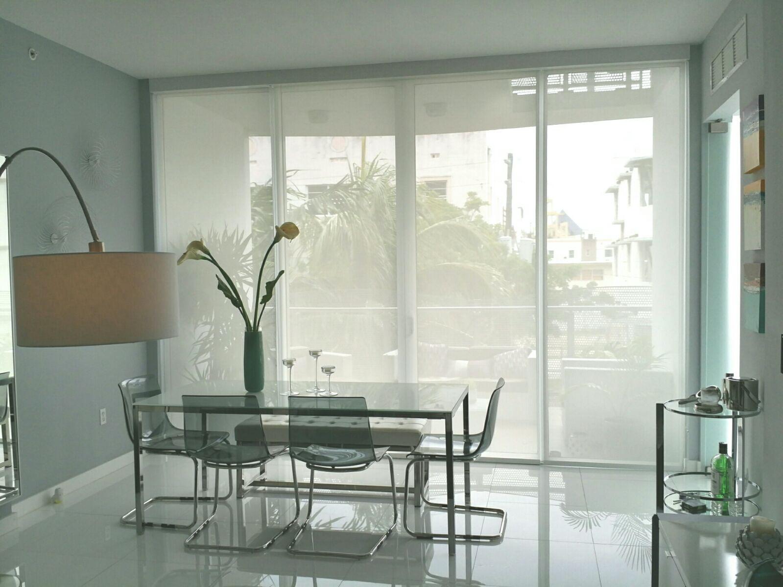 Light-filtering solar screen shades across dining room sliding glass doors