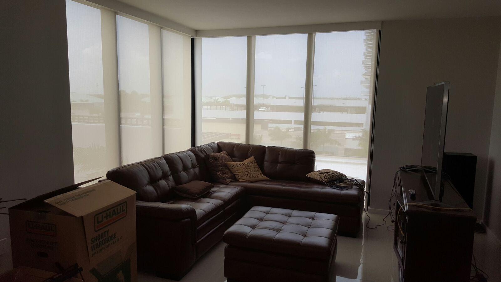 Solar screen roller shades covering corner living room windows