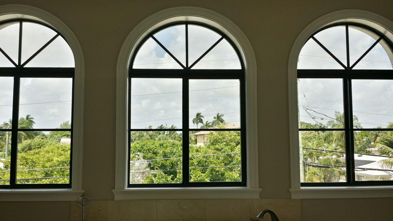 Before: uncovered arched windows above a bathtub