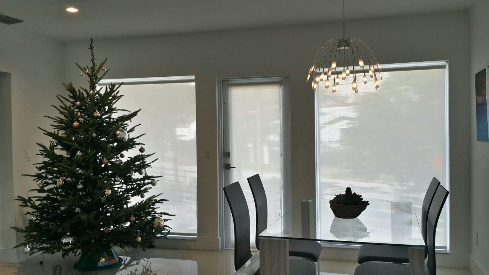 White solar screen shades across dining room windows and a glass door