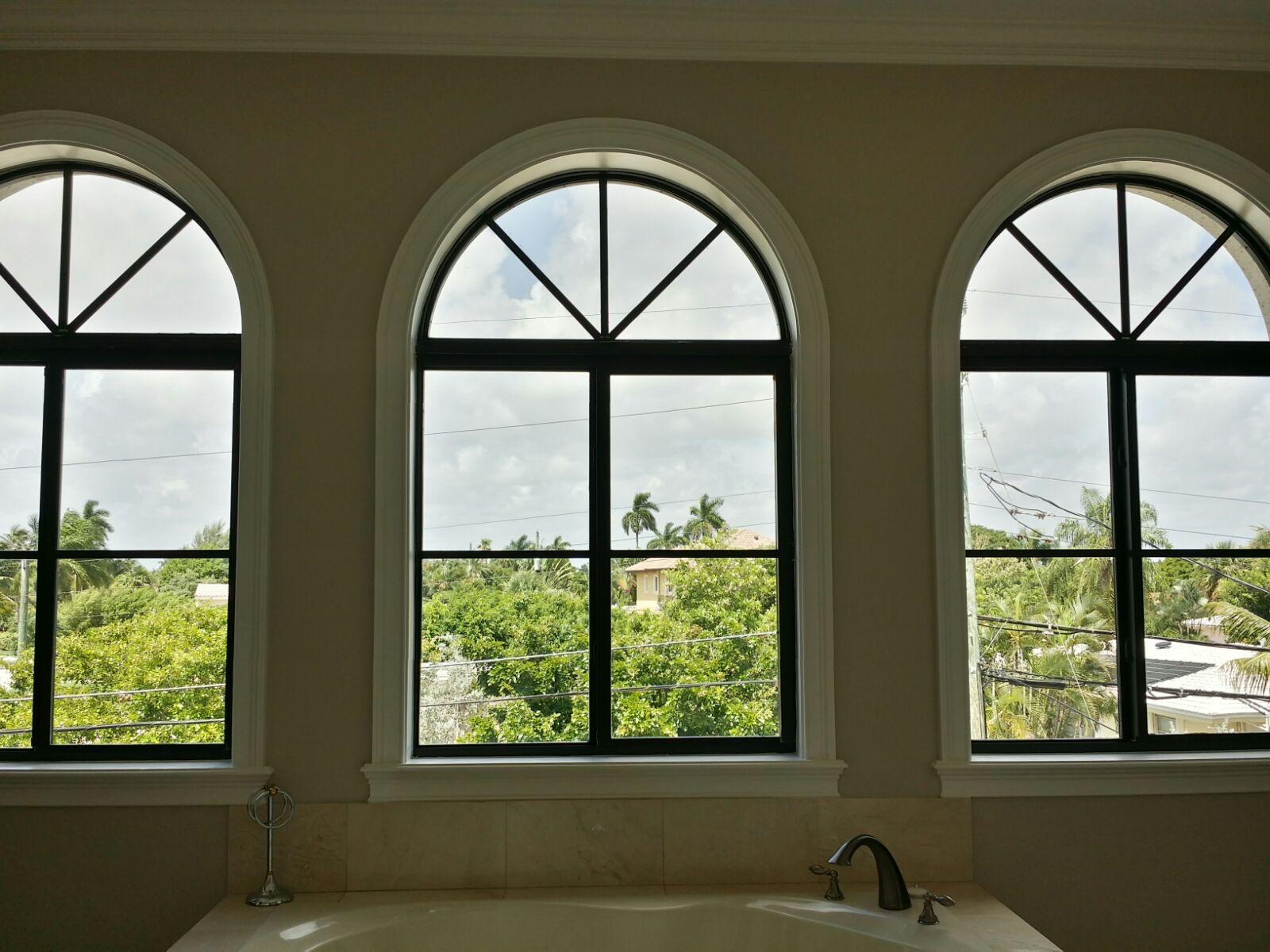 Three uncovered arched windows above a bathtub