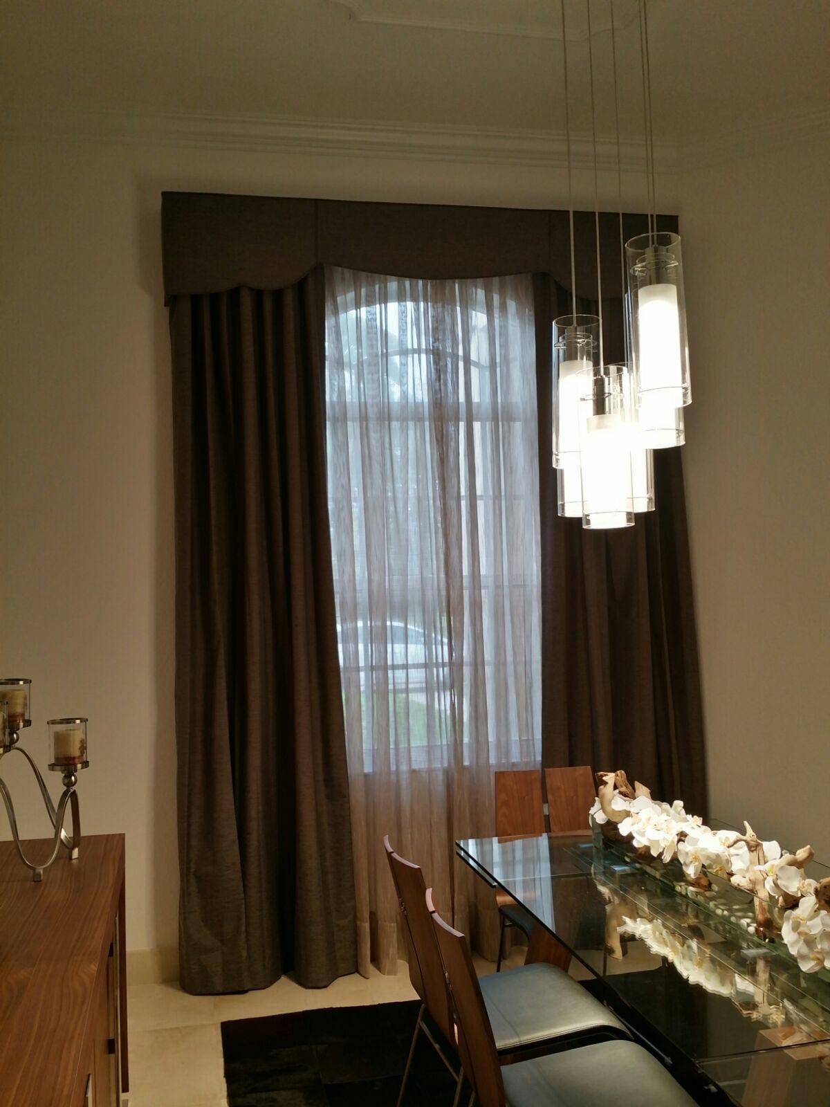 Dining room window with sheer curtains, dark drapery and valance